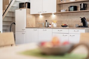 A modern kitchen with white cabinets, a wooden countertop, and a built-in microwave. - MYALPS Mühlhof (Oetz)