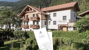 A traditional Alpine-style building with a wooden balcony, a sign reading 'MyAlps.at', and a garden in the foreground. - MYALPS Mühlhof (Oetz)