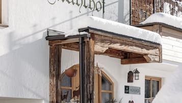 Ein Gebäude mit einem Schild, auf dem 'Mühlfhof' steht, und einer hölzernen Struktur im Vordergrund.