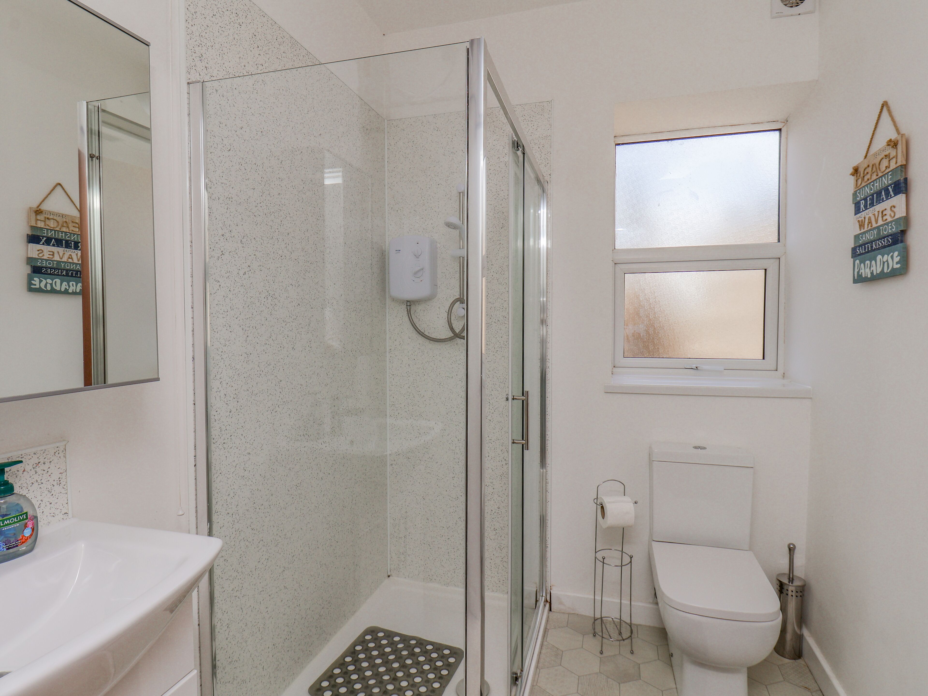 Een badkamer met een douchecabine, toilet en wastafel.