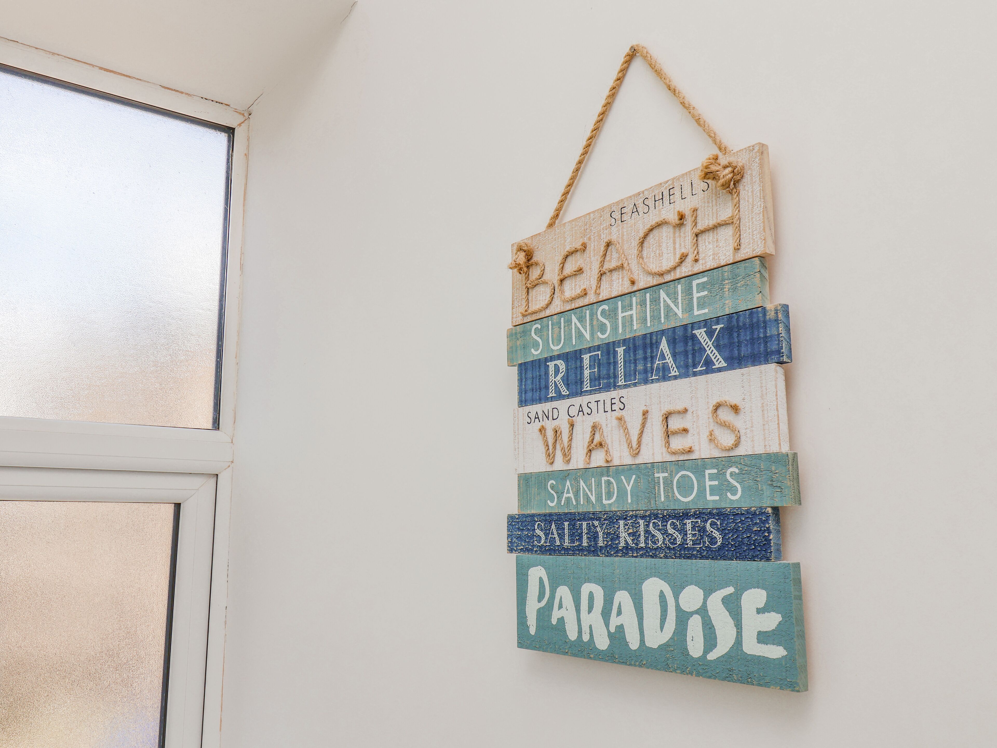 Un letrero en la pared con palabras como 'PLAYA', 'SOL', 'RELÁJATE' y 'PARAÍSO'.