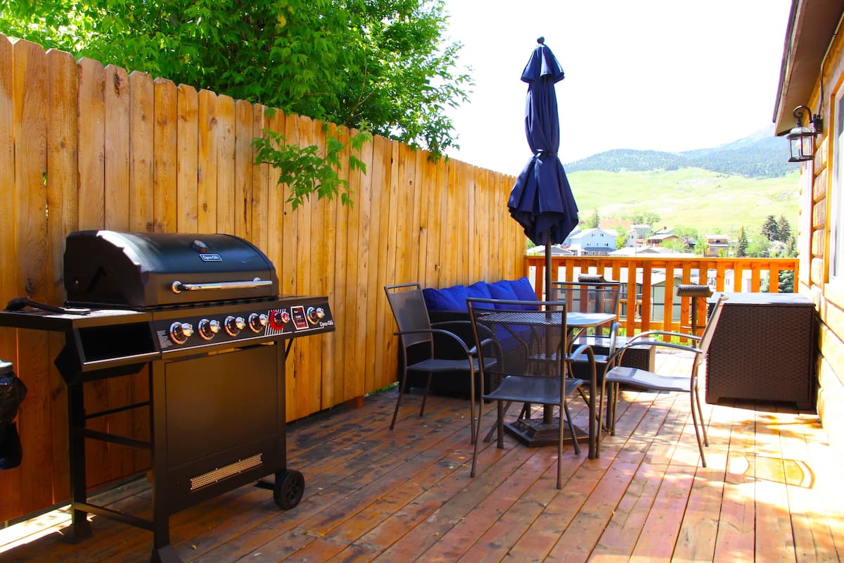 Une terrasse extérieure avec un barbecue, des chaises et une table.