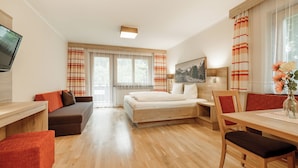 A hotel room with a bed, a desk, a sofa, and a dining table.