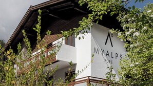 A building with a sign reading 'MYALPS PURE' and a wooden balcony.