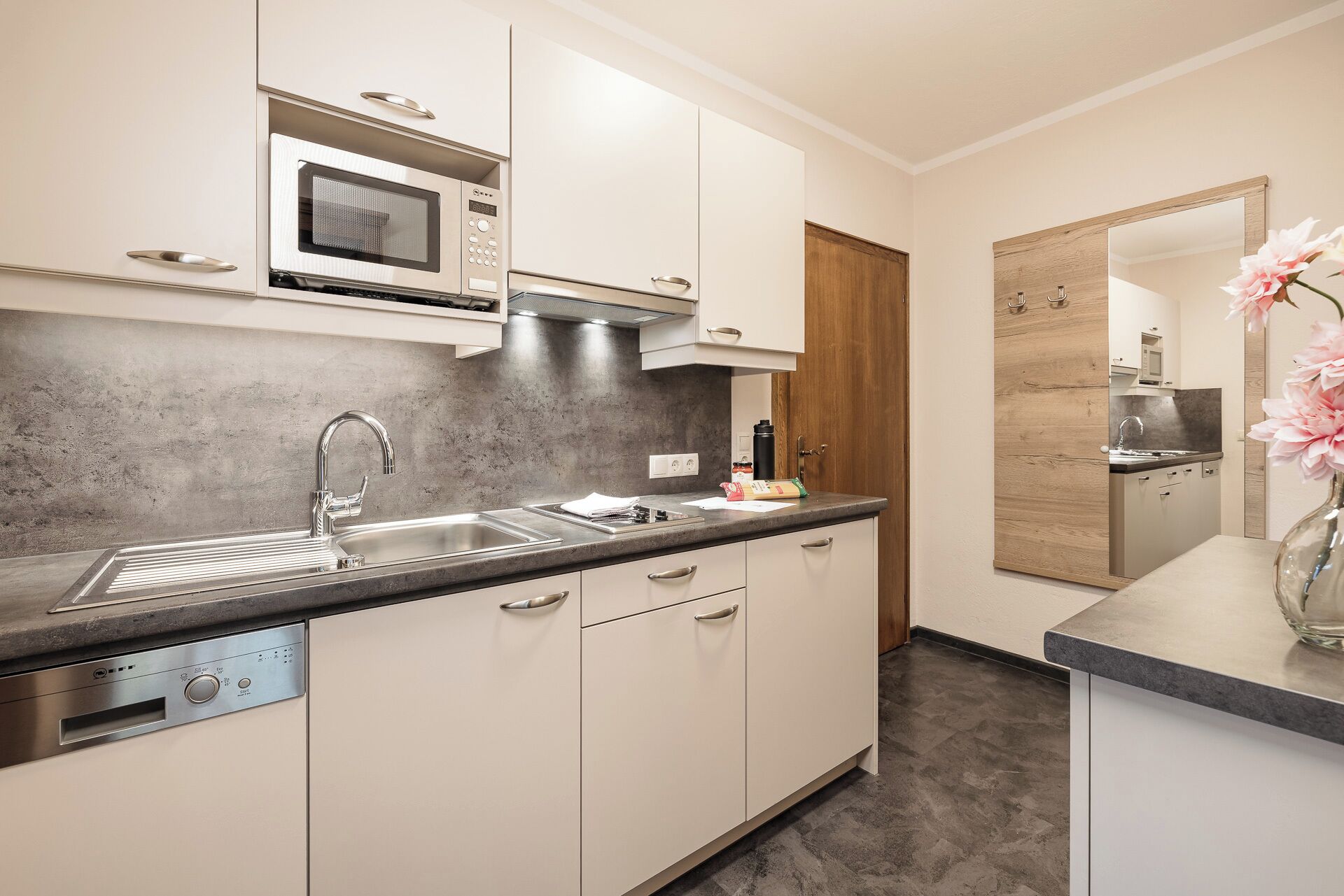 A modern kitchen with white cabinets, a stainless steel sink, and a microwave.