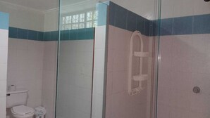 A bathroom with a glass-enclosed shower, a toilet, and a trash bin. - Shalom Home90 Bella Habitacion, Cerca a Centros Comerciales (Barranquilla)