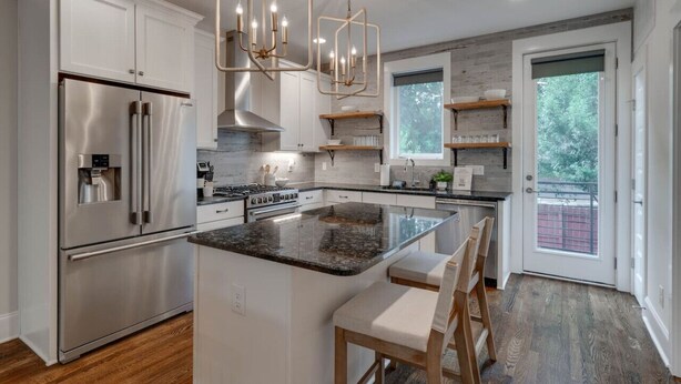 Una cocina moderna con electrodomésticos de acero inoxidable, una isla central e iluminación colgante.