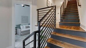 Una escalera de madera con barandillas de metal negro que conduce a un piso superior.