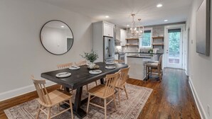 Una cocina moderna con armarios blancos, electrodomésticos de acero inoxidable y una mesa de comedor de madera oscura con sillas.