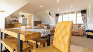 A modern living room with a wooden dining table, leather chairs, and a sofa. - Picturesque cottage with views (Warmfield)