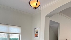 Un salon moderne avec un canapé d’angle gris, une table basse en bois et un lustre.