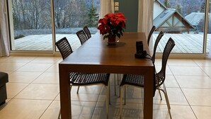 A dining area with a wooden table and chairs, a potted plant, and large windows offering a view of a mountainous landscape. - Appartement Les Orres Chef Lieu (Les Orres Chef Lieu)
