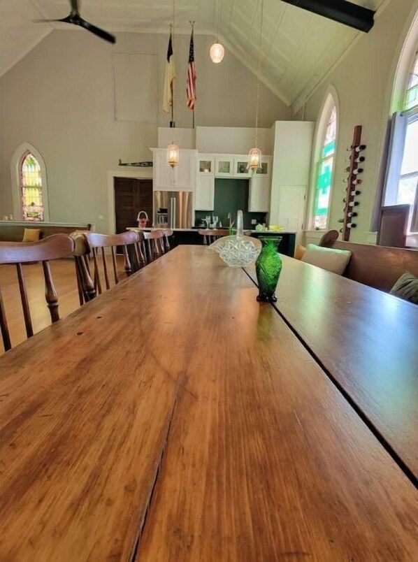 Enjoy meals in this elegant dining room with a long table, high ceiling, and chandelier.