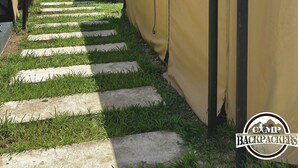 Un chemin menant à un bâtiment sur lequel est affiché un panneau indiquant : « Bravo Team, tireurs d’élite ».