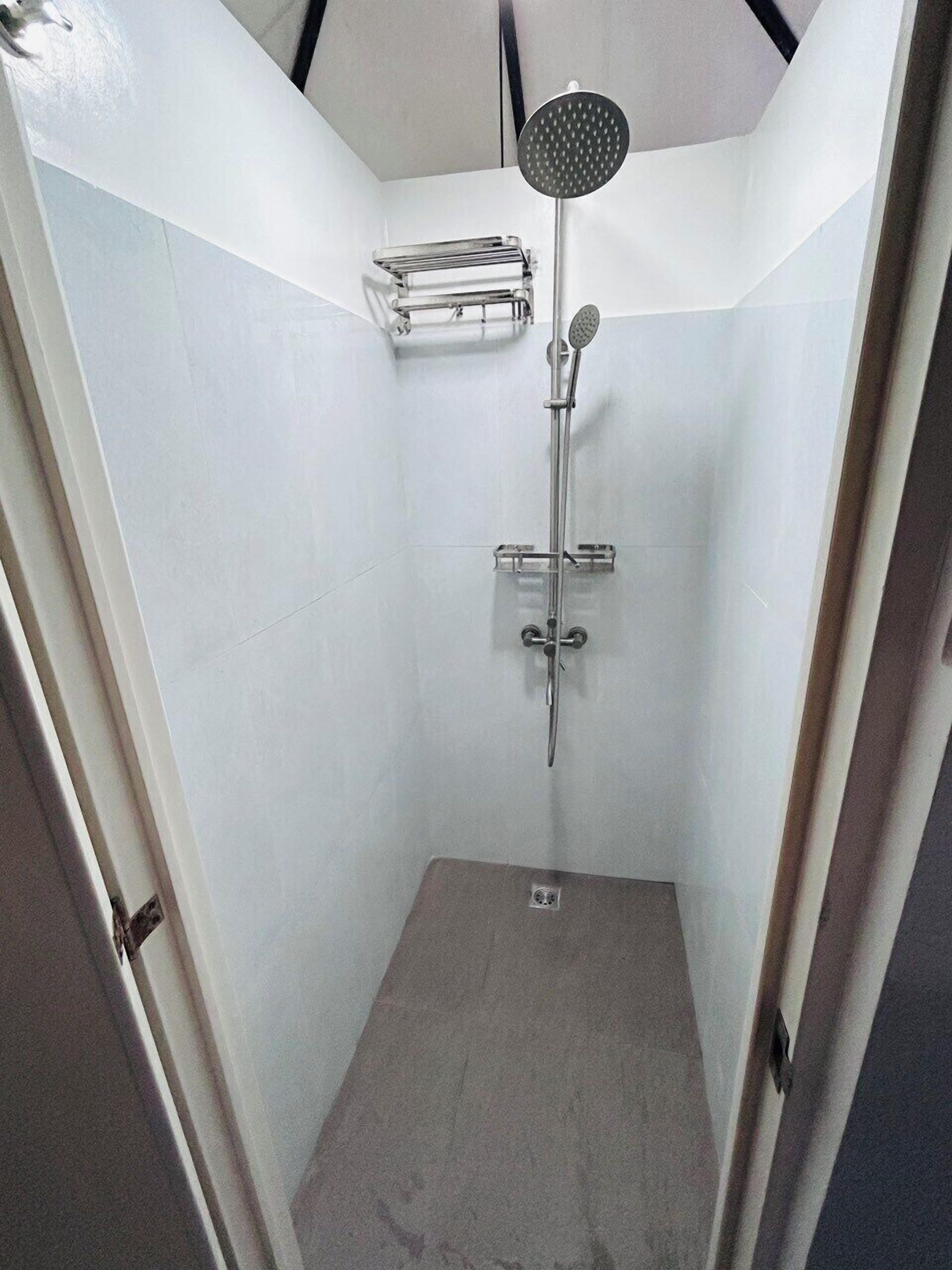 A small, enclosed shower area with a handheld showerhead and a wall-mounted faucet.
