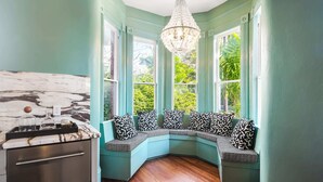 A corner seating area with a marble countertop, a chandelier, and a view of greenery outside. - Grand Maloney Hotel (Key West)