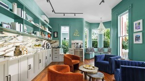 A modern living room with teal walls, a marble countertop, and blue upholstered sofas. - Grand Maloney Hotel (Key West)