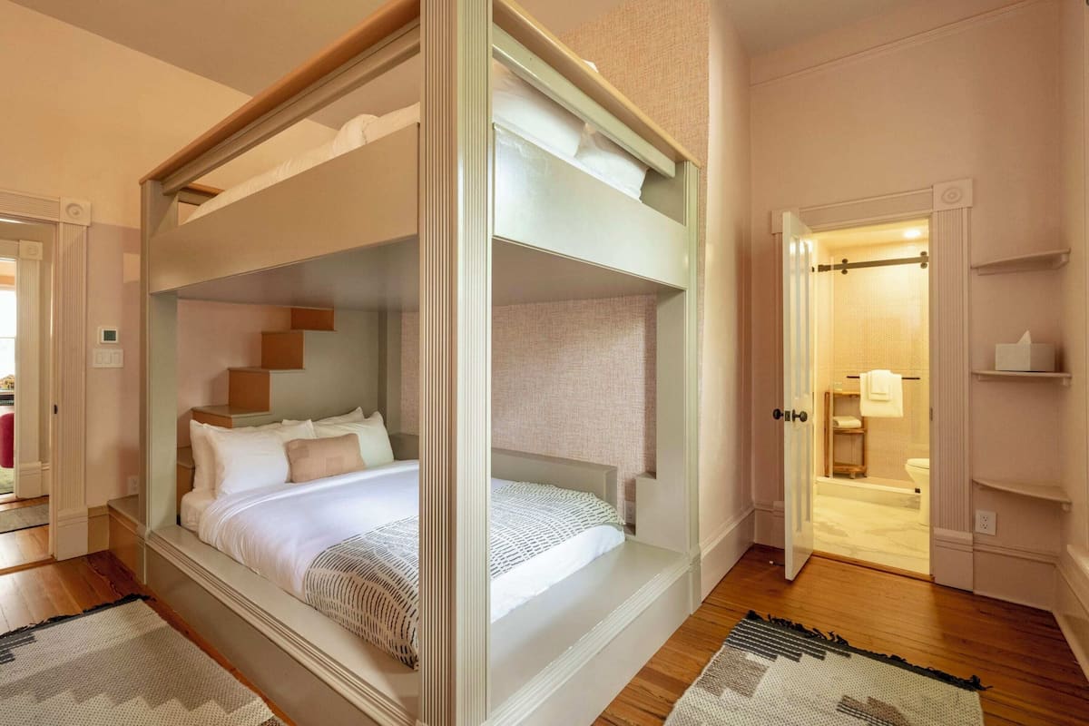 A modern bedroom with a bunk bed, a walk-in closet, and a bathroom with a glass shower.
