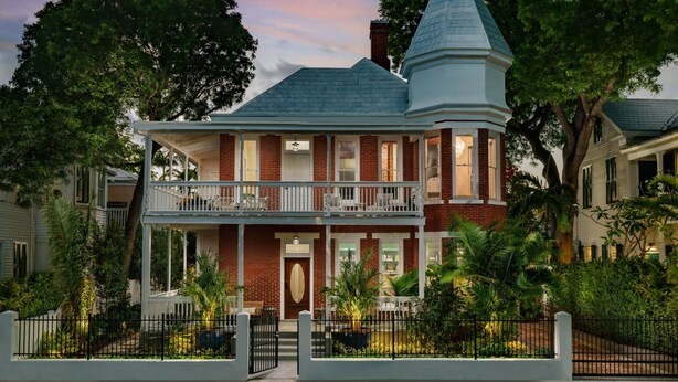 A two-story Victorian-style house with a prominent tower, a balcony, and a front porch. - Grand Maloney Hotel (Key West)