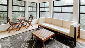 Ein geräumiger Raum mit hohen Decken, großen Fenstern, einem Sofa, einem Couchtisch und einem Deckenventilator.