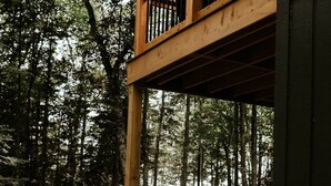 Eine Holzterrasse mit zwei Stühlen und Blick auf Wald und See.