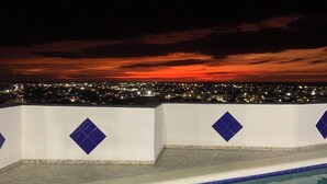 Une piscine offrant une vue sur la ville au coucher du soleil.