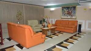 Un salon avec deux canapés orange, un fauteuil beige et une table basse agrémentée d’objets décoratifs.