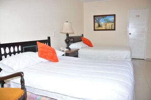 Een hotelkamer met twee bedden, een nachtkastje met een lamp, een stoel en een deur.