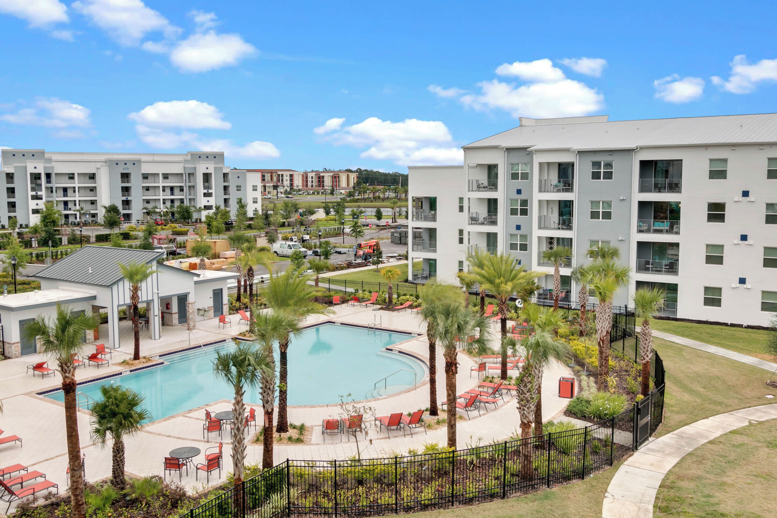 Un hotel moderno con piscina, zona de estar exterior y jardín bien cuidado.