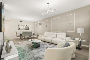 Una sala de estar moderna con un sofá, sillones, una mesa de centro y un comedor con sillas y una mesa.