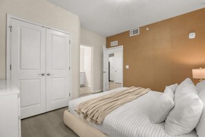 Un dormitorio con una cama, una mesita de noche, un espejo y una puerta.