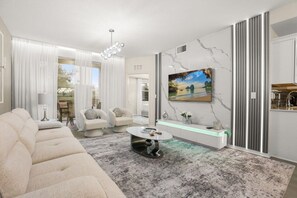 Una sala de estar moderna con un sofá, sillones, una mesa de centro y un cuadro en la pared.