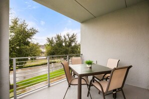 A balcony with a table and chairs, a potted plant, and a view of a road and trees. - Mickey-Themed Bedroom! Sleeps 8 • Storey Lake - 4751-201CT (Kissimmee)