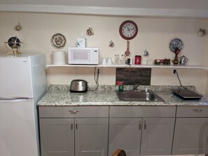 Une cuisine équipée d’un réfrigérateur blanc, d’un four à micro-ondes, d’un grille-pain, d’un évier et de placards.