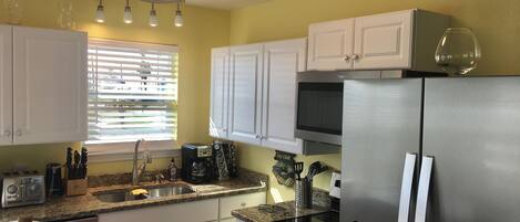 A kitchen with white cabinets, a stainless steel refrigerator, a microwave, and a toaster.