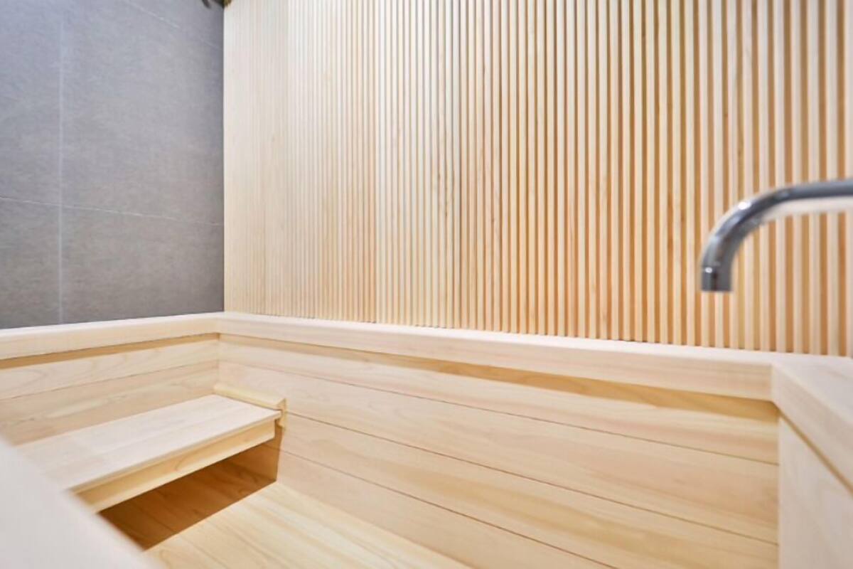 A wooden sauna with a sloped floor and a metal faucet.