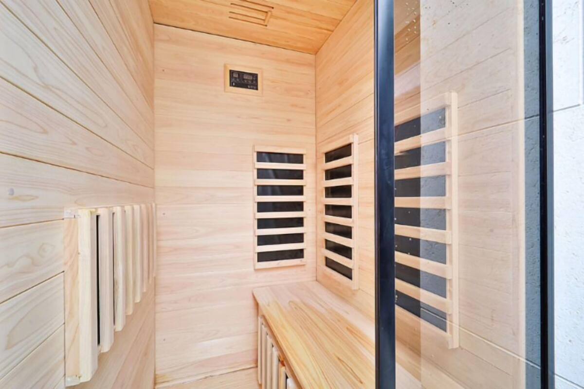 A sauna with wooden walls and benches, featuring ventilation slats and a visible plaque on the wall.
