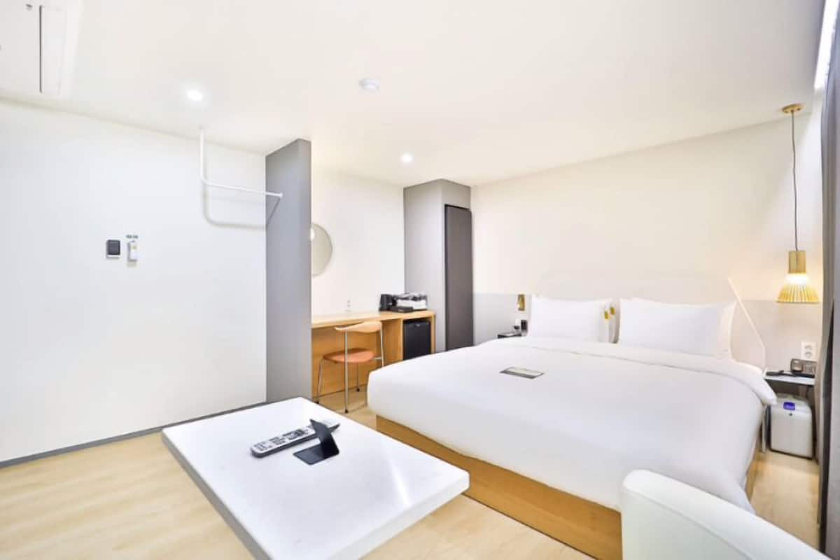 A modern hotel room with a large bed, a desk, and a chair.