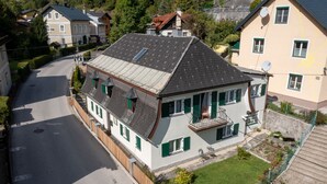 A two-story house with a sloped roof, a balcony, and a small garden. - Katzerhaus Ebensee (Ebensee)
