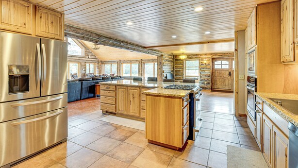 A spacious kitchen with wooden cabinets, a stainless steel refrigerator, and a large island.