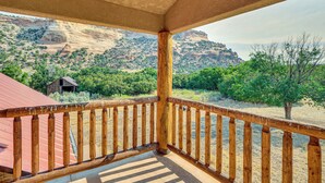A wooden balcony with a view of a mountainous landscape and a rustic building.