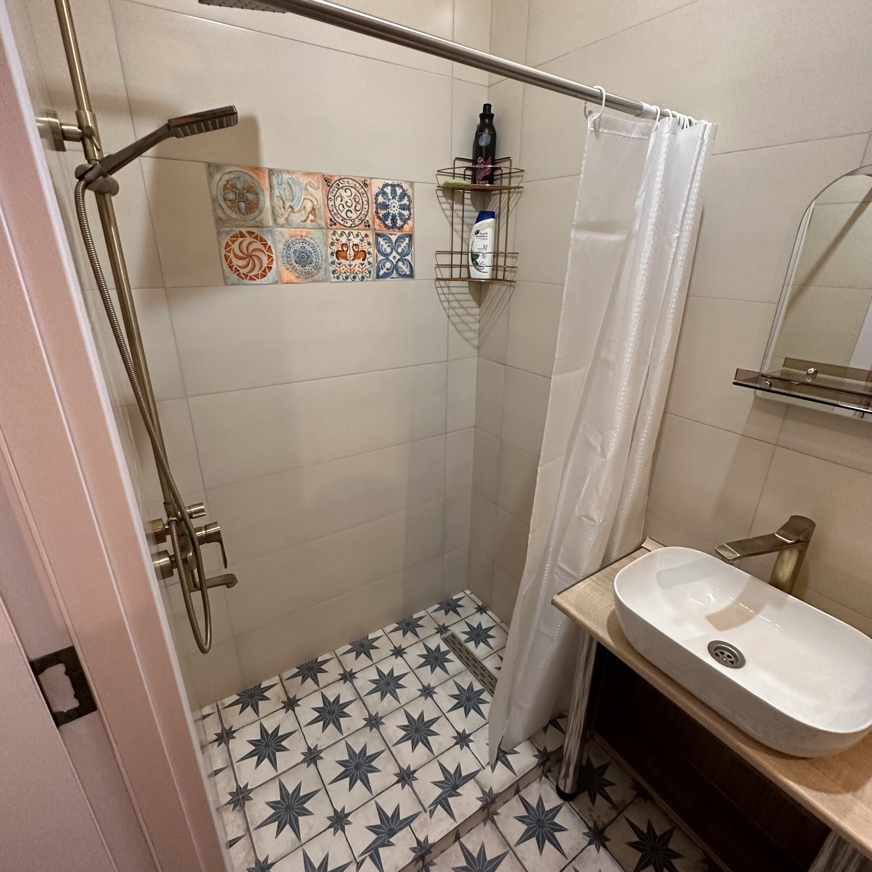 Un baño con ducha, lavamanos y suelo de baldosas.