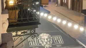 Un balcón con vistas a una calle por la noche, con edificios que tienen balcones y luces colgantes.