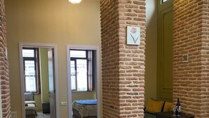 Una habitación amplia con suelo de madera, una pared decorativa de ladrillo y una cama con cabecera verde.
