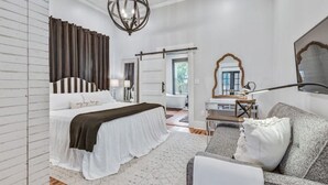 A bedroom with a large bed, a sofa, a desk, and a mirror. - Poppy & Rye House: one block from the Silos (Waco)