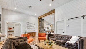 A spacious living room with a large brown sofa, a wooden coffee table, and a bright orange chair. - Poppy & Rye House: one block from the Silos (Waco)
