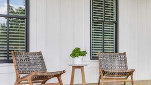 Two wicker chairs with woven seats and backs, a small round wooden table with a potted plant, and a window with blinds. - Poppy & Rye House: one block from the Silos (Waco)