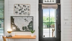 A black door with a window, a map, and a shelf with a lamp and a plant. - Poppy & Rye House: one block from the Silos (Waco)