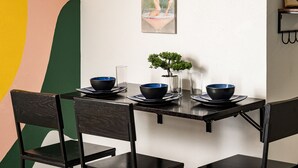 Ett matbord med svarta stolar, en liten krukväxt och svarta skålar på tallrikar.