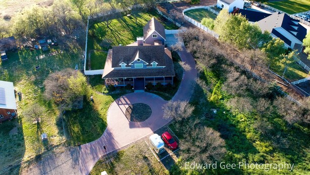 Luchtbeeld van een groot, gelijkvloers huis met een oprit die uitkomt in een ronddraaiende oprit.